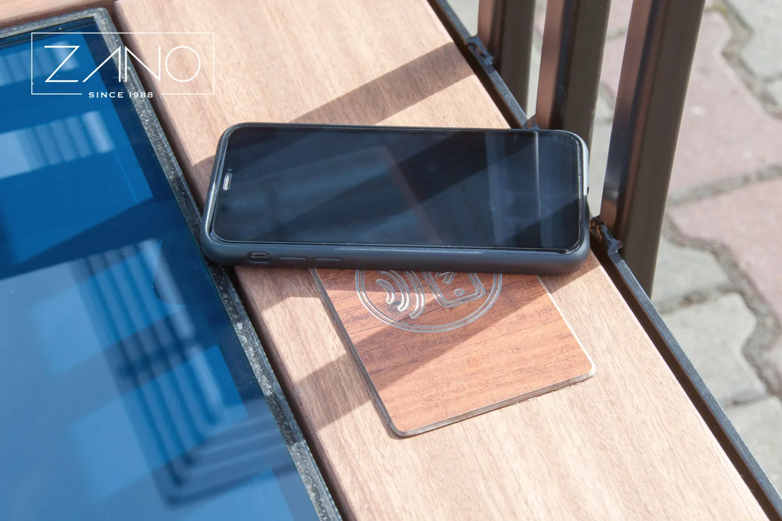 Induktionsladdare för mobiltelefoner i en solcellsdriven bänk i staden